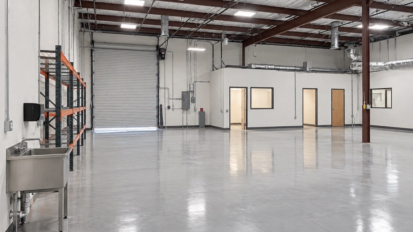 The same industrial suite completed, with a clean insulated deck, new lighting, finished white walls, enclosed offices, and a ground and sealed concrete floor.